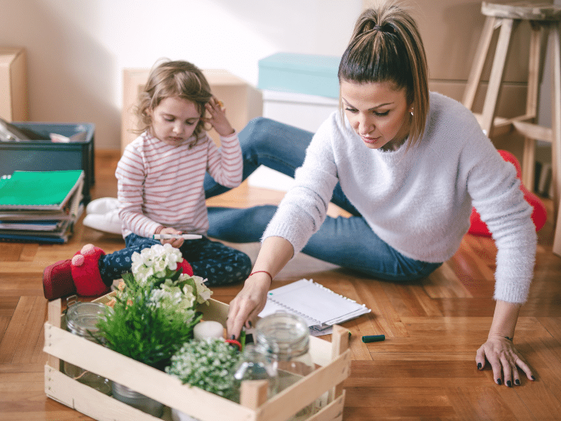 Mom and her daughter on the floor going over a check list with flowers sitting in front of them.