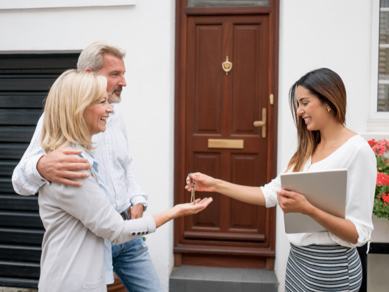 Older couple receiving their new house keys from their realtor.