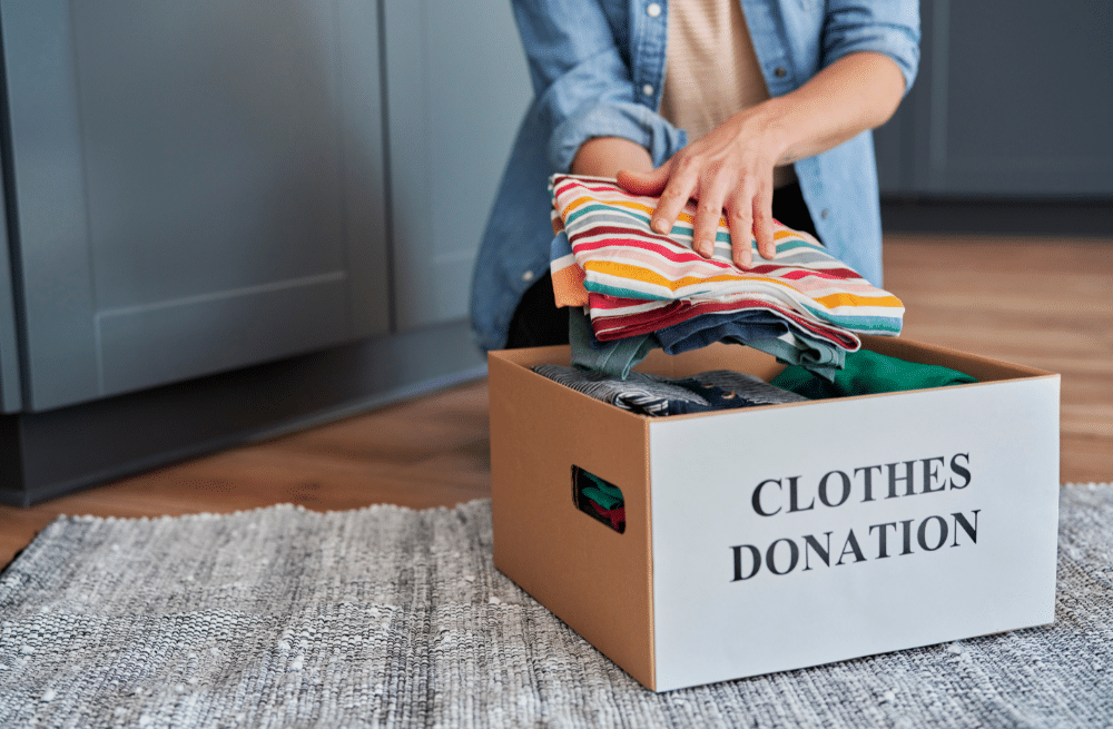 Person putting clothes in a small cardboard box labeled