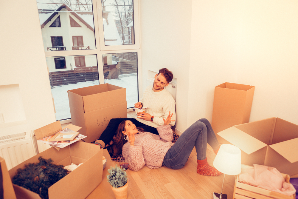 A couple laying on the floor of their house after unpacking.