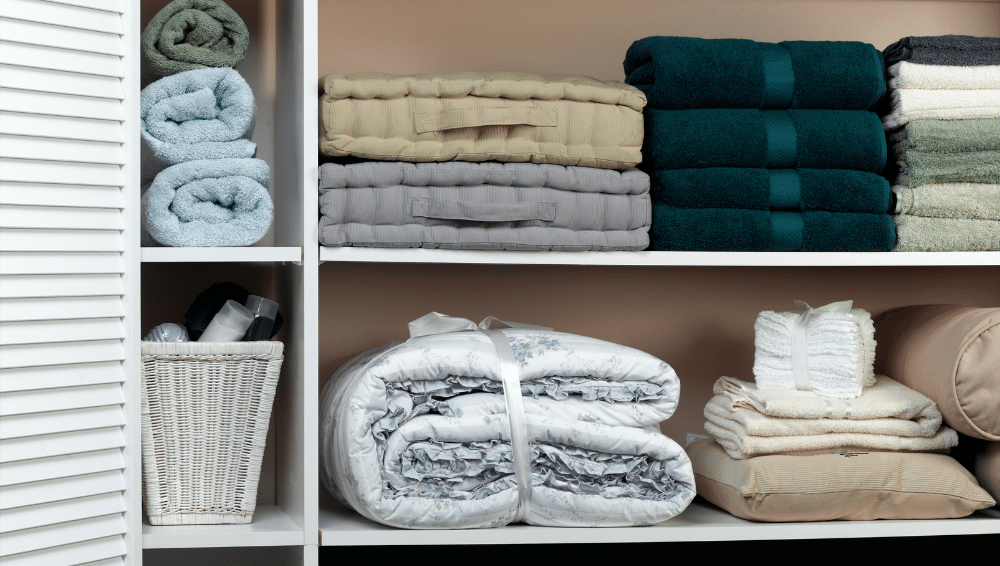 Closet with towels and sheets on the shelf.